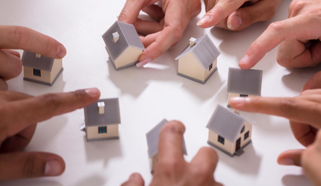 Finger schieben Modellhäuser zusammen - Energiegenossenschaft für Wärmeversorgung