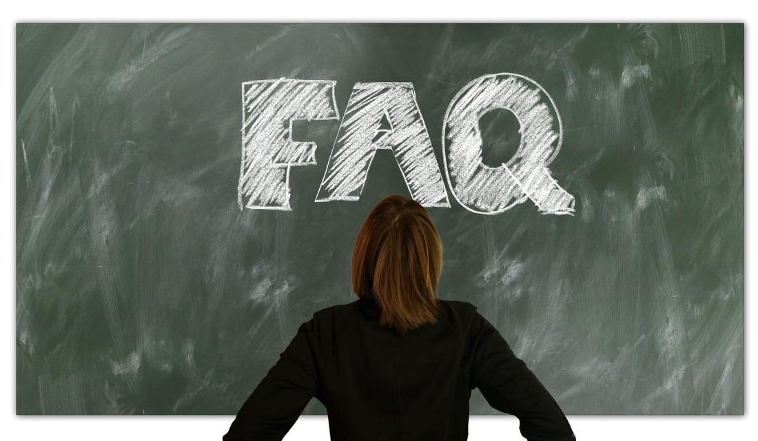 Eine Frau steht vor einer Tafel, auf der mit Kreide "FAQ" geschrieben wurde.