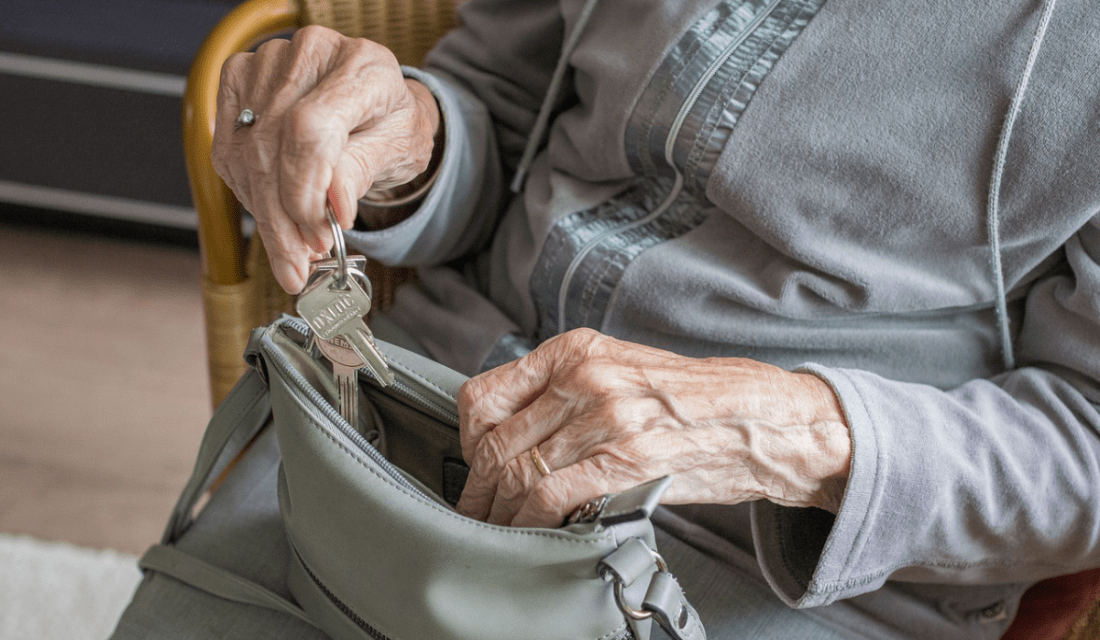 Eine ältere Frau holt ihren Schlüssel aus ihrer Handtasche.
