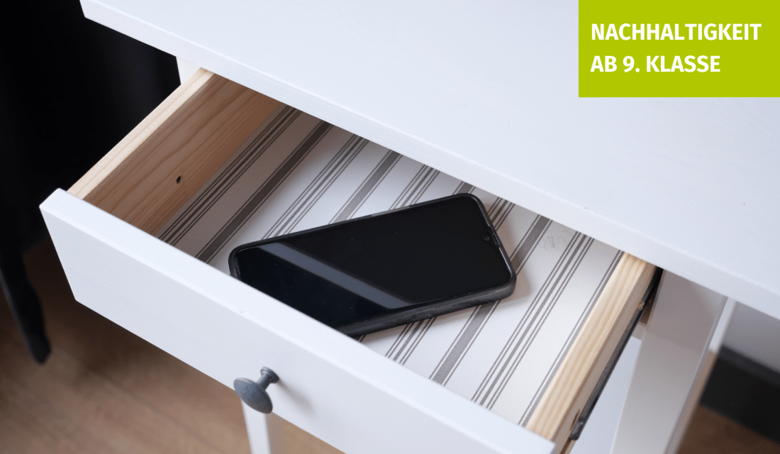 Eine geöffnete Schublade in der ein Smartphone liegt