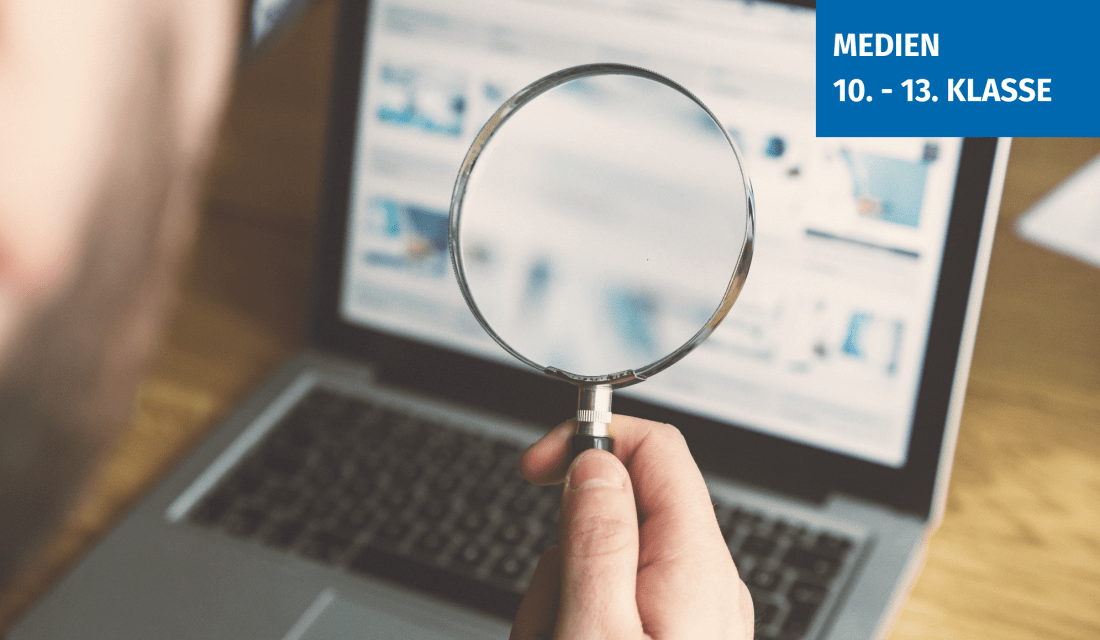 Eine Lupe vor einem Bildschirm, der Bildschirm ist unscharf