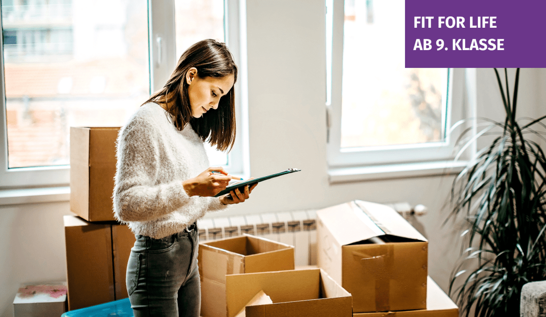 eine junge Frau steht mit Klemmbrett vor Umzugskartons in einer hellen Wohnung