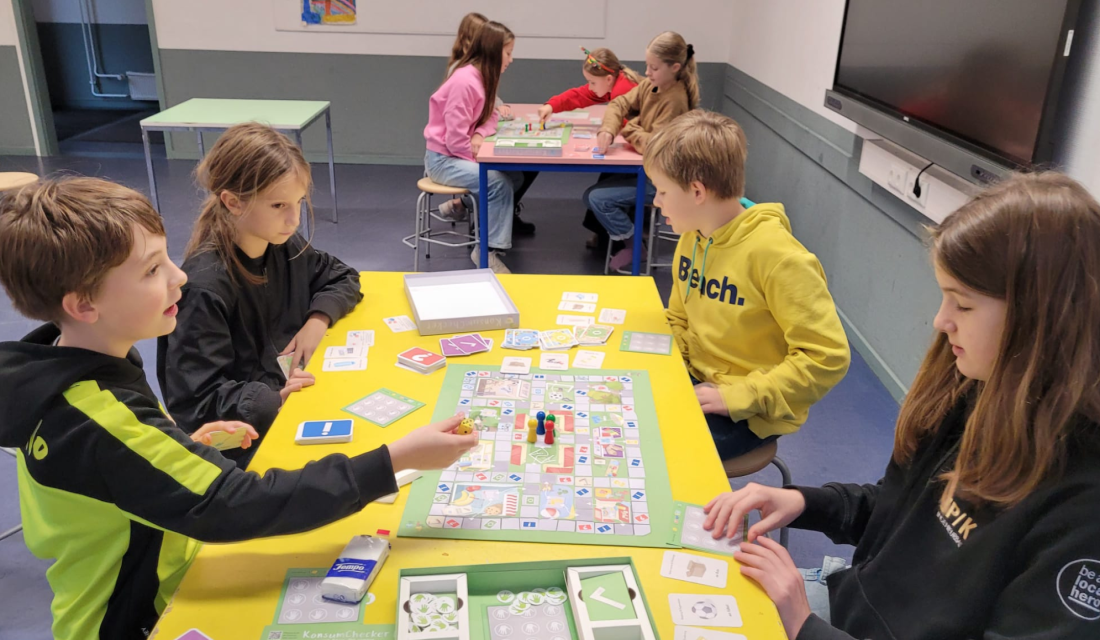 Kinder sitzen an Tischen und spielen das Brettspiel KonsumChecker der VZSH