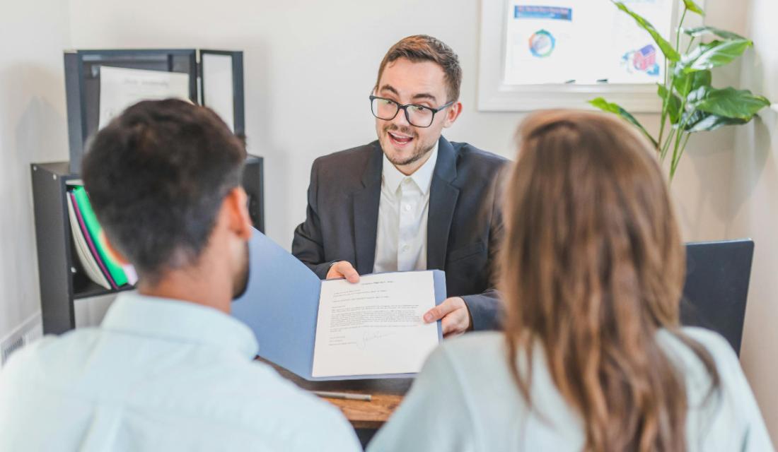 Mann berät ein Ehepaar in einem Büro