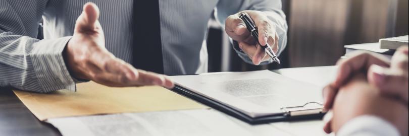 Hände und Unterlagen eines Rechtsberaters am Schreibtisch