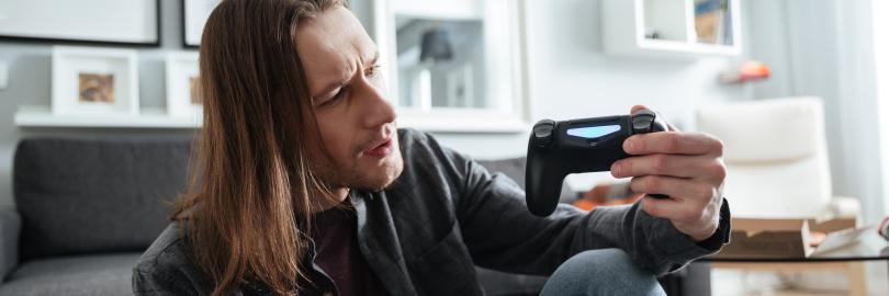 Ein Mann sitzt mit einem Controller auf dem Boden und schaut verwirrt.