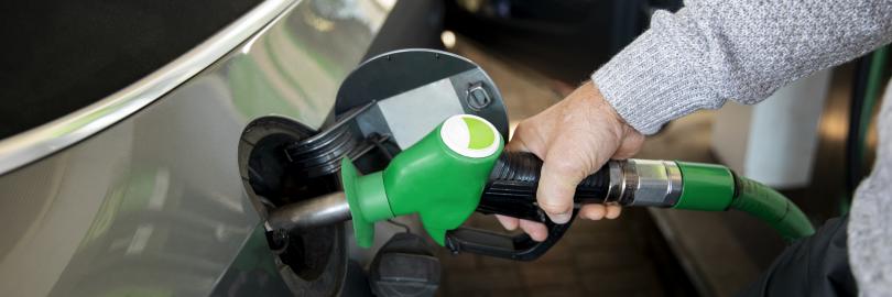 Eine Hand hält an einer Tankstelle eine Zapfpistole in die Tanköffnung