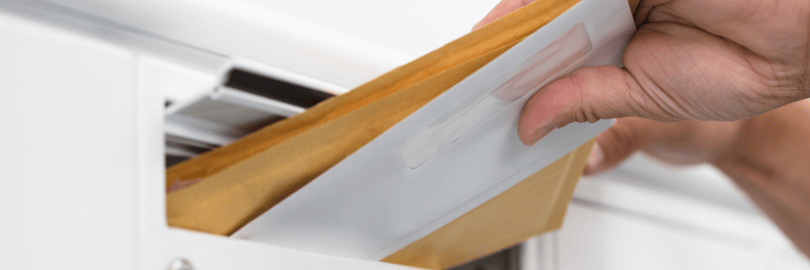 Mehrere Briefe werden in einen Briefkasten geworfen