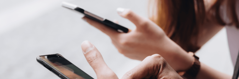 Jugendliche sitzen nebeneinander mit Smartphones in den Händen.