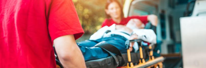 Zwei Sanitäter schieben eine Bare mit einem Patienten in einen Krankenwagen