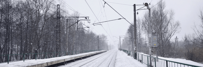 Eine eingeschneite Bahnstrecke mit Oberleitungen und Bäumen