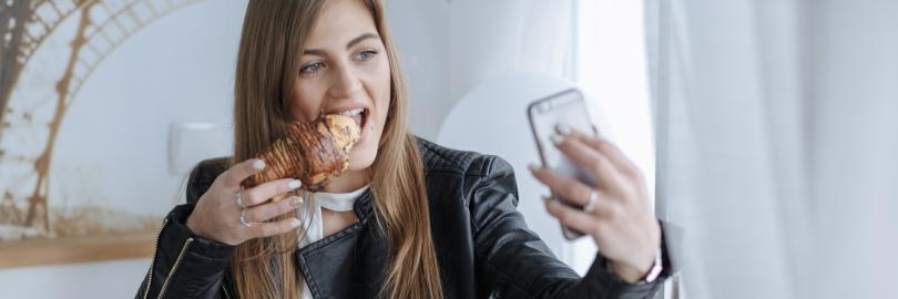 Ein Influencerin filmt sich, wie sie ein Croissant isst
