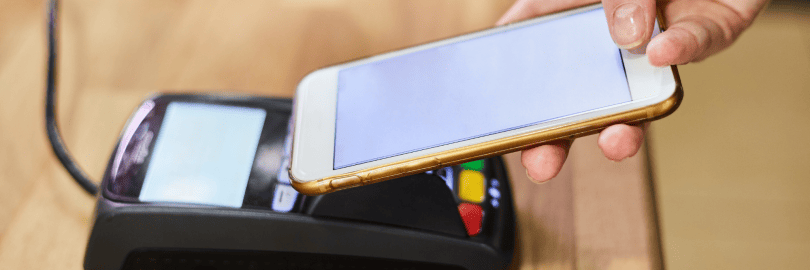 Ein Smartphone wird zur Bezahlung an eine Kartenlesegerät gehalten