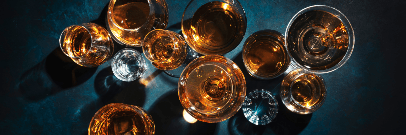 Blick von oben auf verschieden Schnapssorten in Gläsern auf einem Tisch.