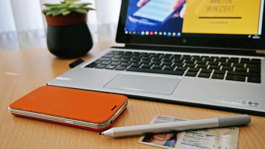 Personalausweis und Smartphone auf Schreibtisch mit Laptop