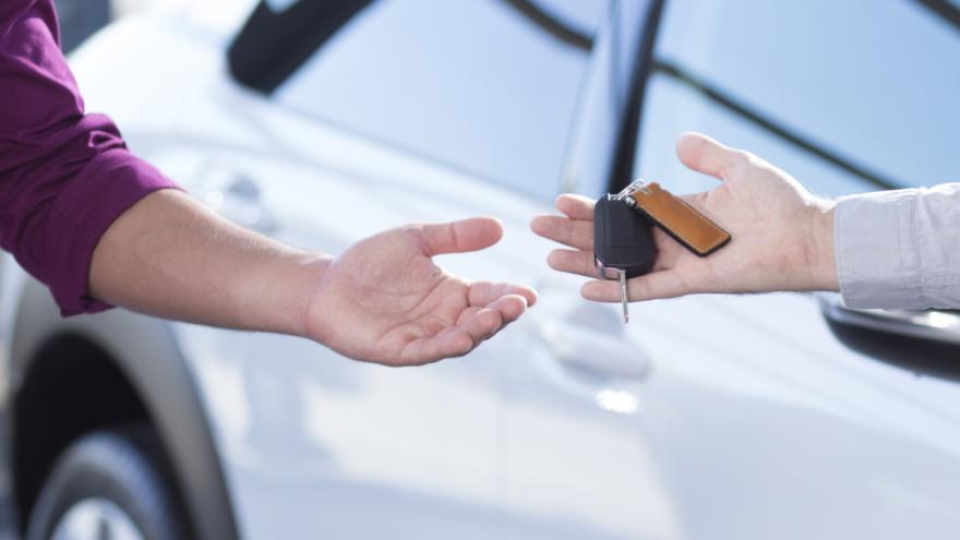 In der Nahaufnahme von zwei Händen übergibt ein Mann einer Frau einen Autoschlüssel