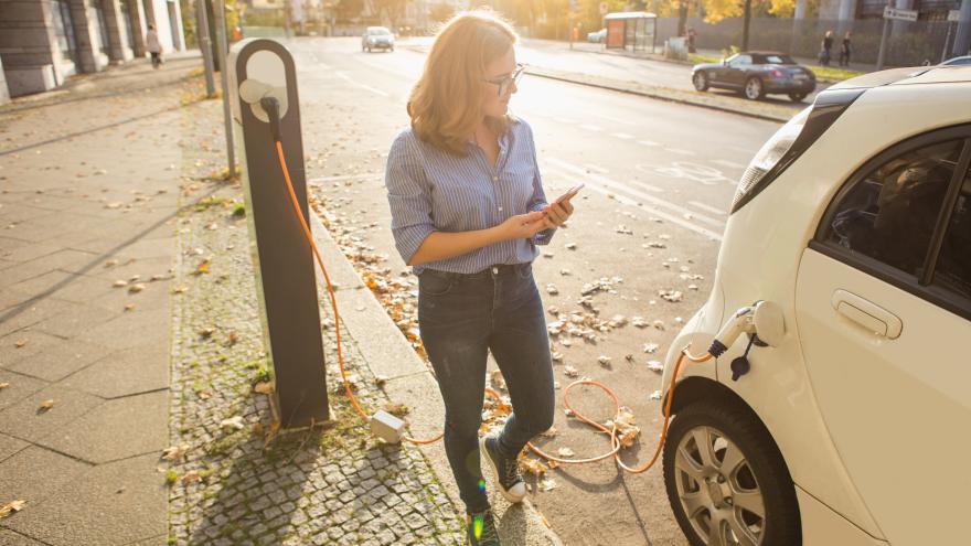 Junge Frau neben E-Auto