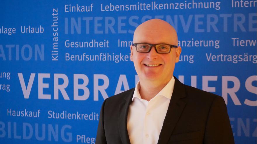 Stefan Bock, Vorstand der VZSH, Porträt vor blauer Wand