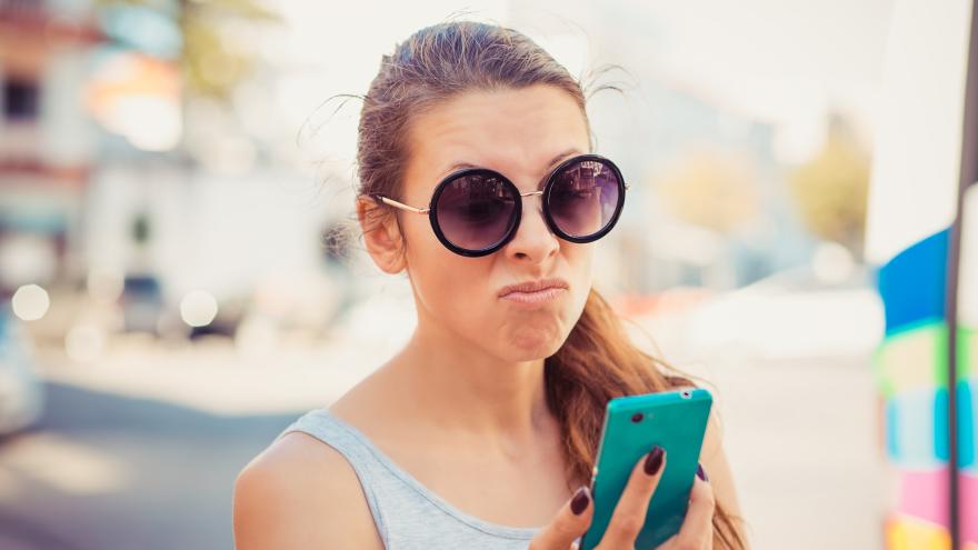 Verbraucher:in schaut skeptisch auf ihr Mobiltelefon
