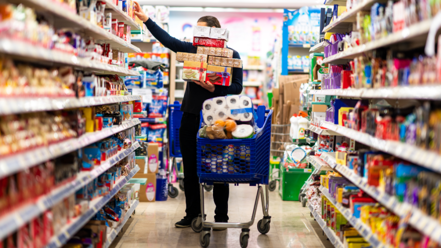 Mann kauft im Supermarkt Lebensmittel und legt sie in den vollen Einkaufswagen