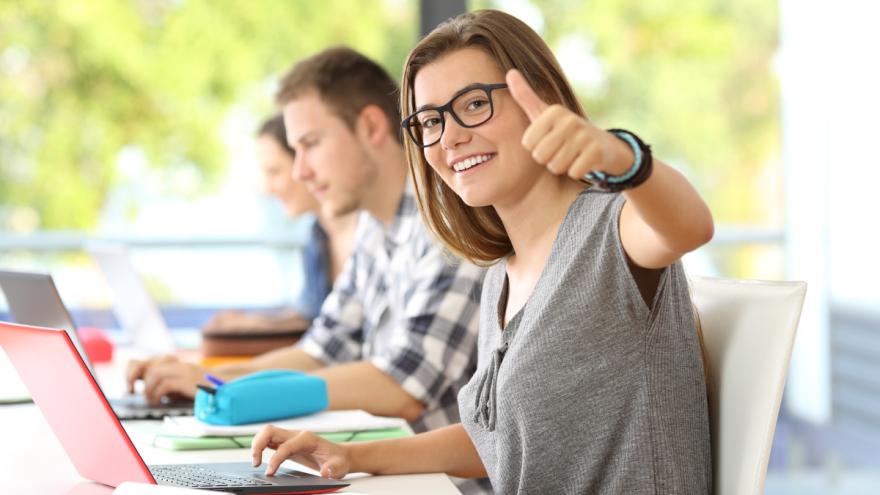 Studenten sitzen in einem Vorlesungsraum vor ihrem Laptop.