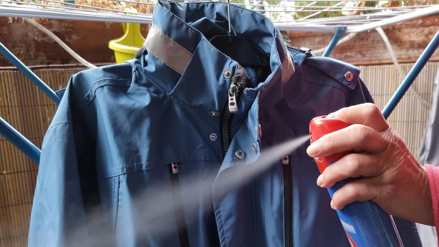 Imprägnierspray wird auf hellblaue Regenjacke gesprüht