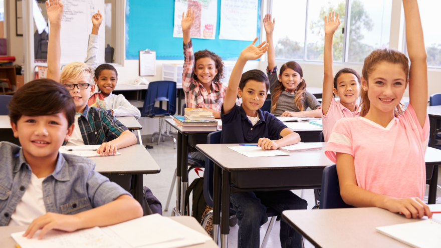 Kinder im Klassenzimmer melden sich eifrig