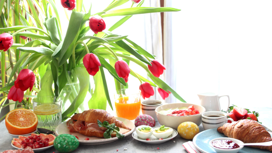 Osterfrühstück mit bunten Eiern und roten Tulpen