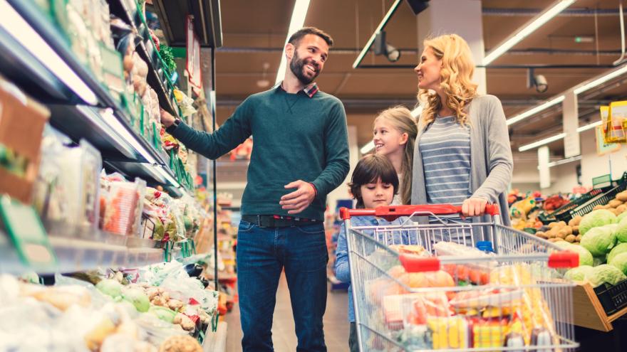 junge Familie mit Kind mit Einkaufswagen im Supermarkt