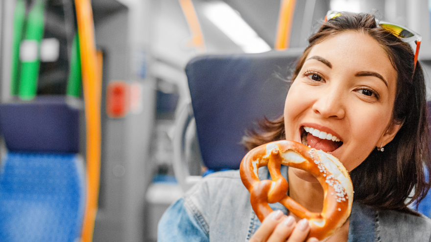 Frau isst eine Bretzel im Zug.