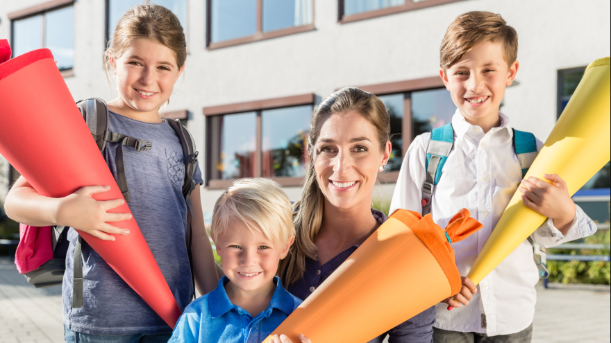 Eine Frau mit drei Kindern und Schultüte.