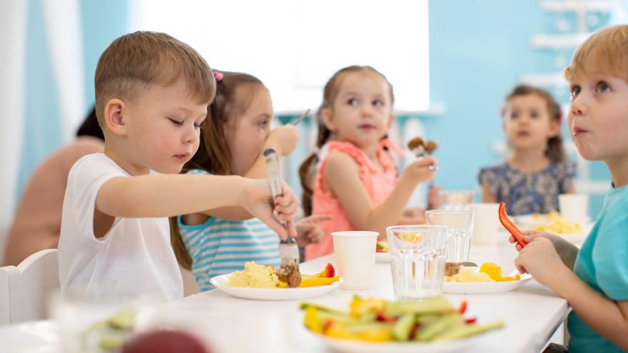 Kinder sitzen in der Kita am Tisch und essen