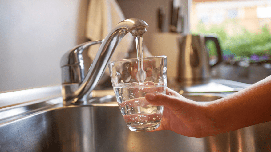 Aus einem Wasserhahn wird frisches Wasser in ein Glas gefüllt