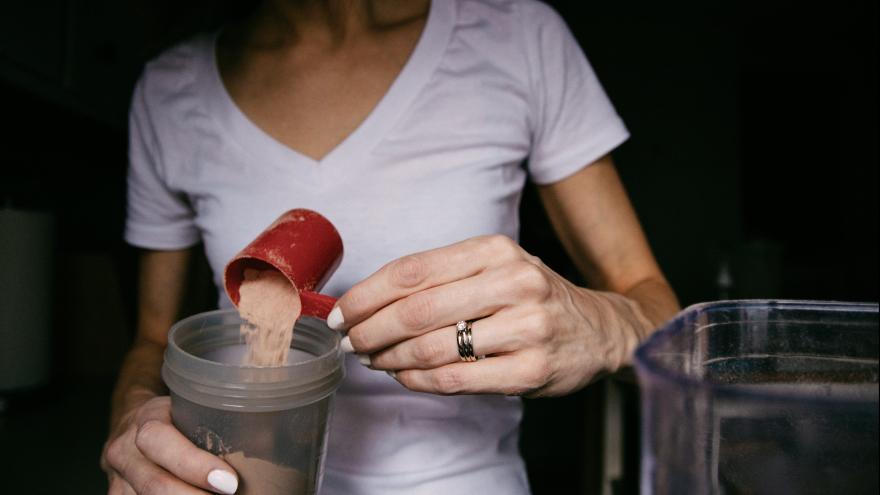 Eine Frau füllt Proteinpulver in einen Messbecher