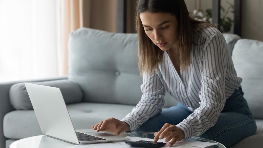 Studienkredit: Eine Studierende rechnet ihre Finanzen mit Laptop und Taschenrechner durch.