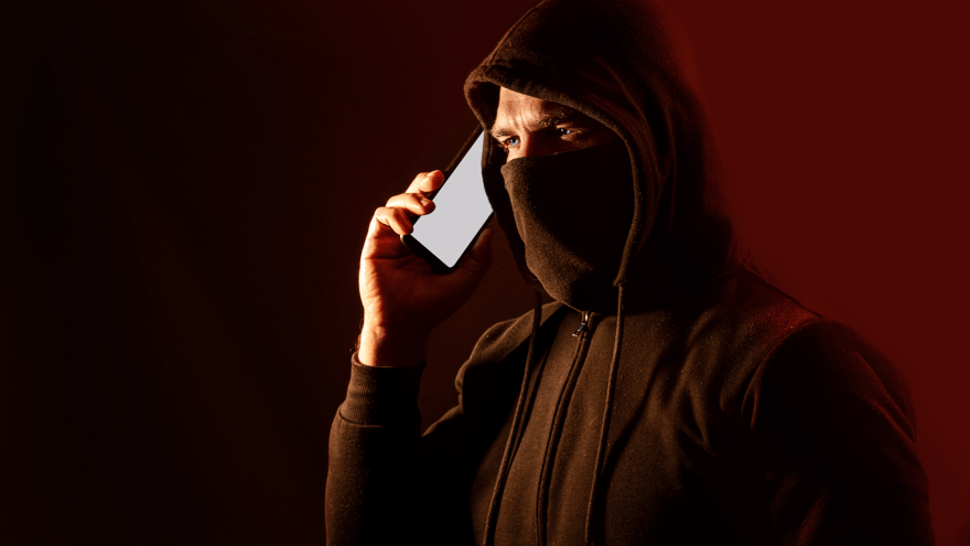 Ein maskierter Mann telefoniert mit einem Smartphone
