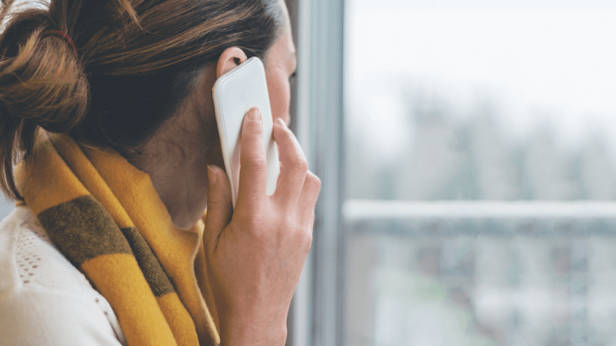 Eine Frau telefoniert und blickt aus einem Fenster.