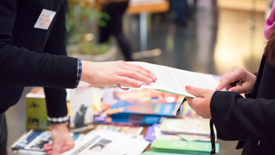 An einem Infostand wird ein Vertrag zwischen zwei Menschen besprochen