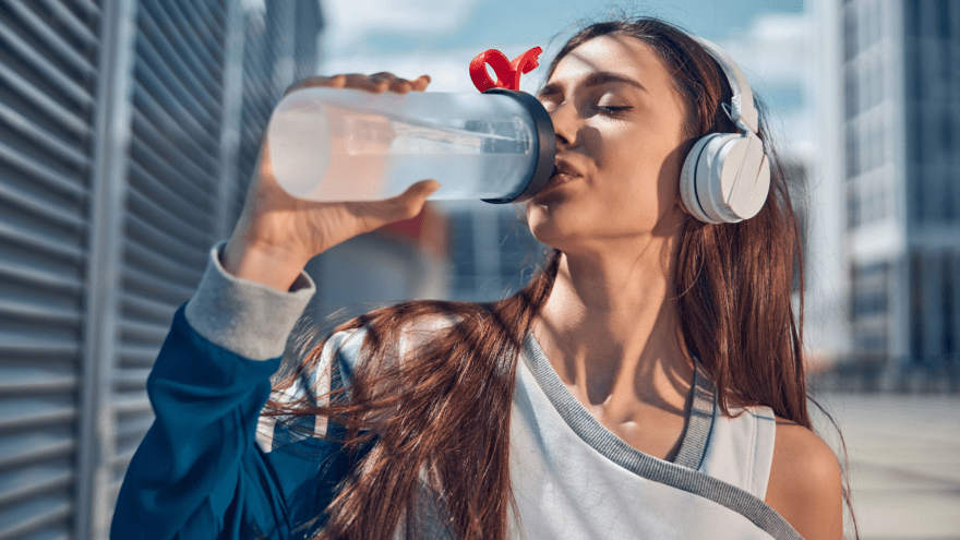 Eine Frau trinkt Wasser aus einer Getränkeflasche