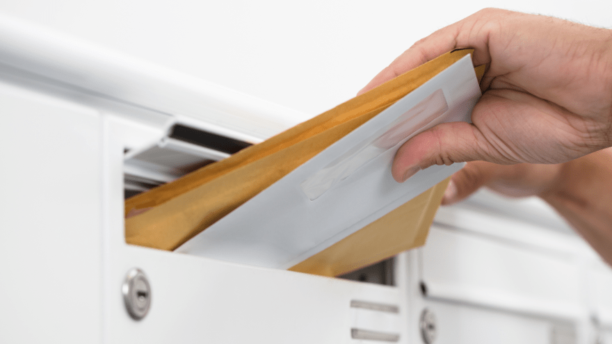 Mehrere Briefe werden in einen Briefkasten geworfen