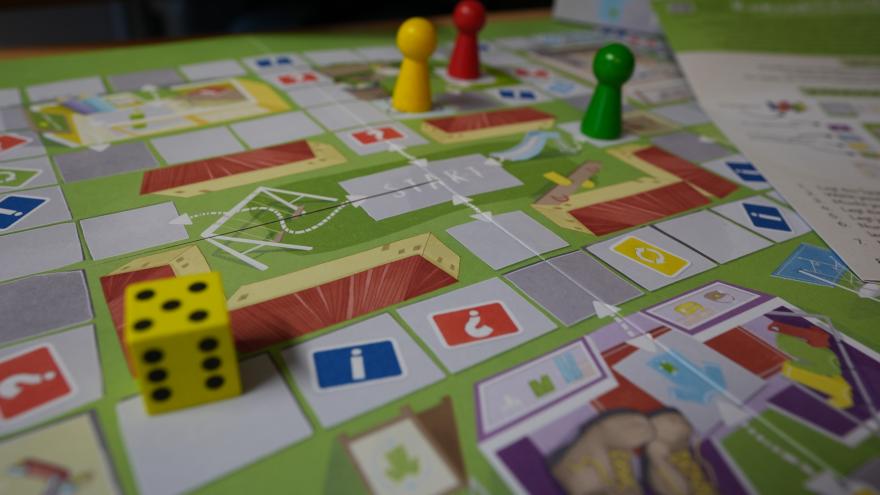 Brettspiel auf dem Spielfiguren und ein Würfel liegen.