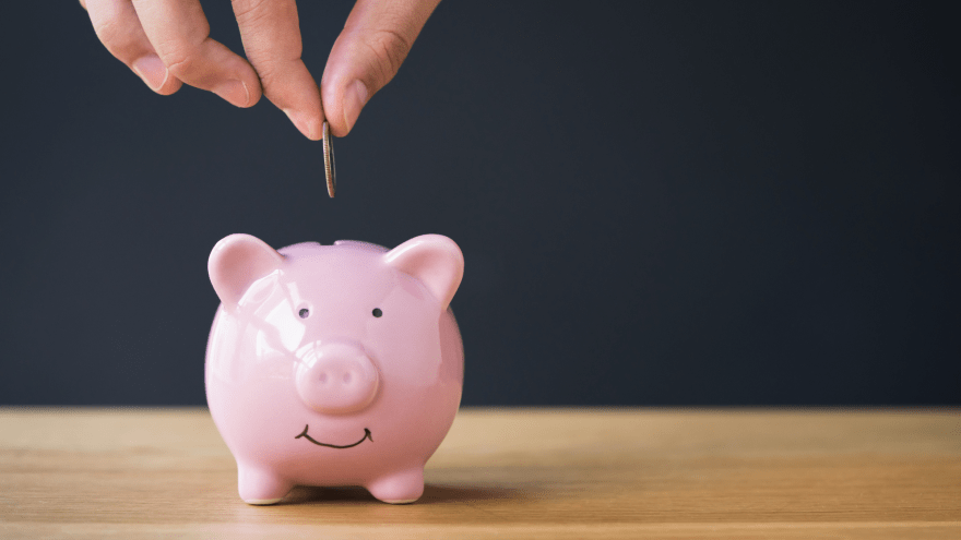 Ein Sparschwein wird mit einer Münze befüllt