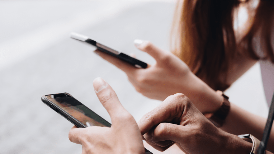 Jugendliche sitzen nebeneinander mit Smartphones in den Händen.