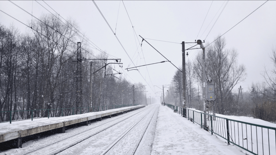 Eine eingeschneite Bahnstrecke mit Oberleitungen und Bäumen