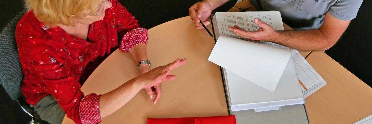 Mann und Frau im Gespräch am Tisch mit Unterlagen, von oben fotografiert