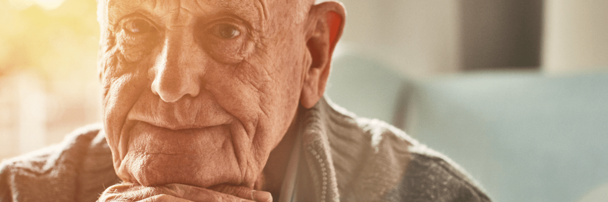 älterer Mann schaut betrübt in die Kamera