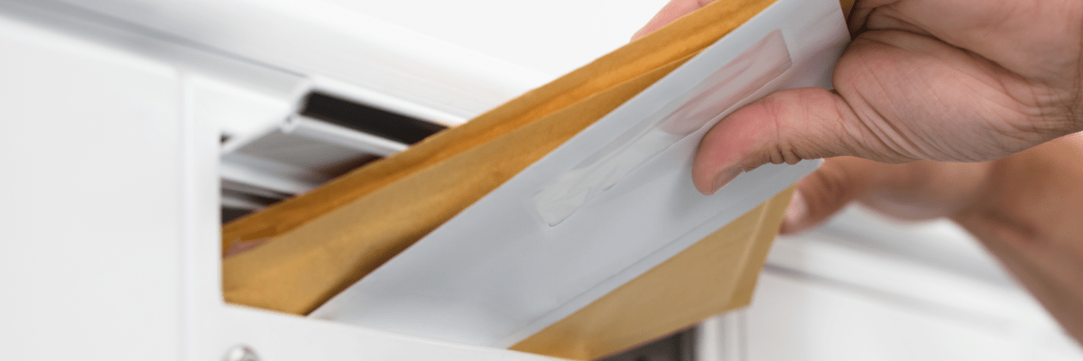 Mehrere Briefe werden in einen Briefkasten geworfen