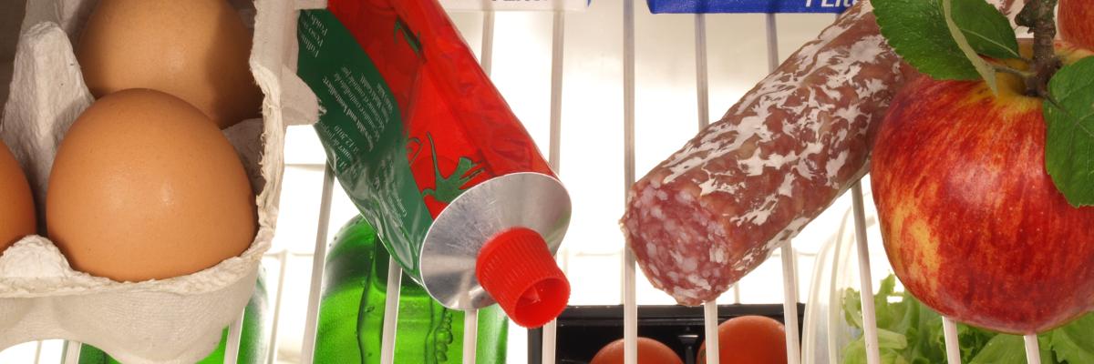 Ein geöffneter Kühlschrank mit Lebensmitteln wie Eiern, Salami, Tomatenmark