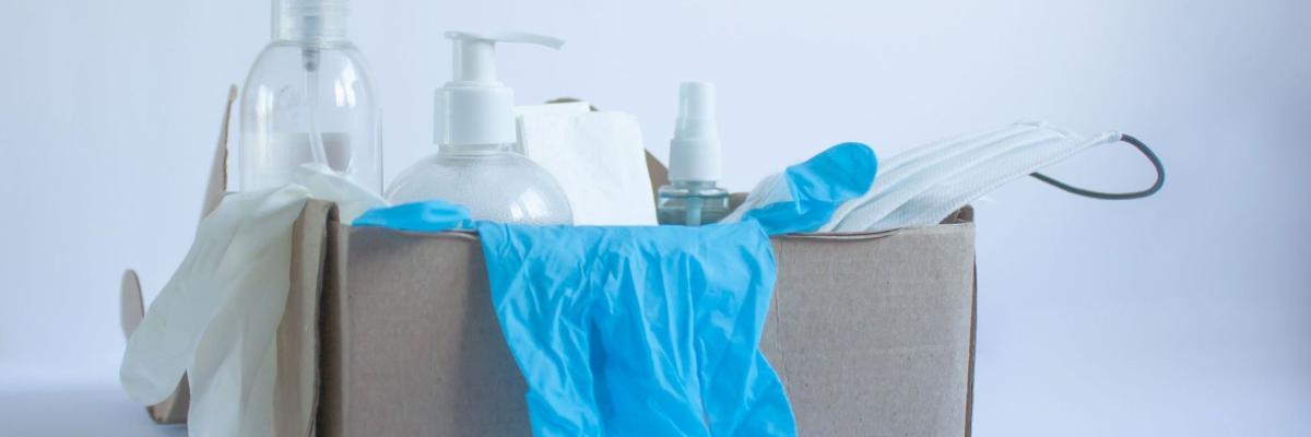 Karton mit Pflegemitteln wie Einmalhandschuhen, OP-Maske, Spray