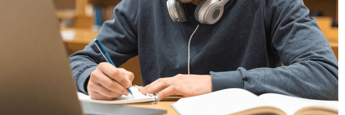 Ein Schüler sitzt in einer Bibliothek vor einem Laptop und lernt